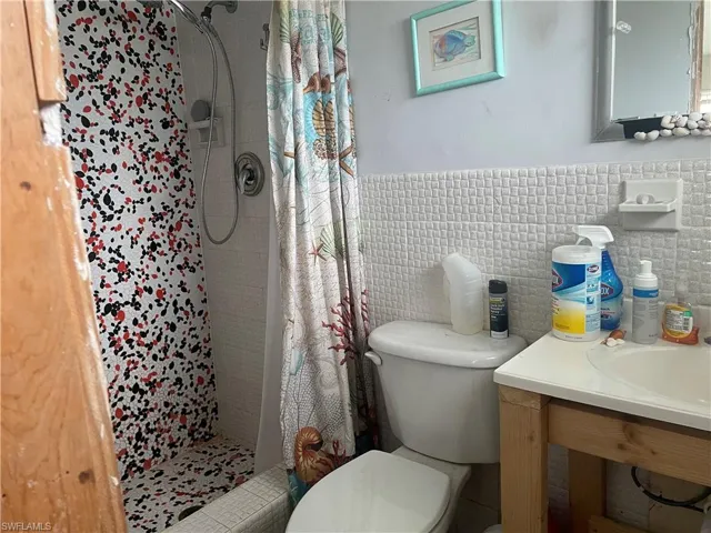 Bathroom featuring vanity, toilet, tile walls, and curtained shower