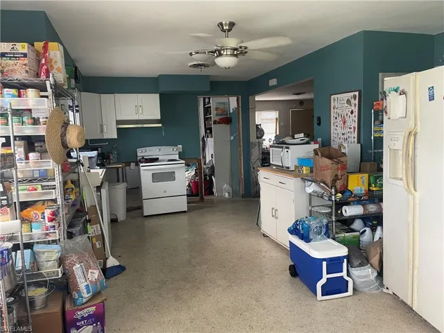 Kitchen with white cabinetry, ceiling fan, and white appliances