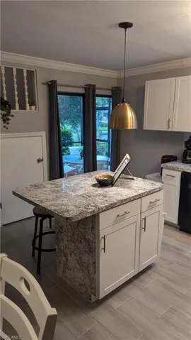 Kitchen with white cabinets, dishwasher, light hardwood / wood-style flooring, pendant lighting, and a kitchen island