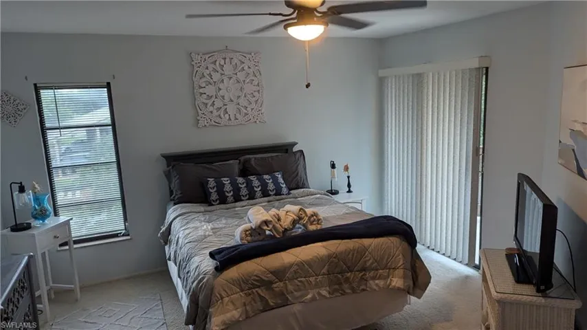 Carpeted bedroom with multiple windows and ceiling fan