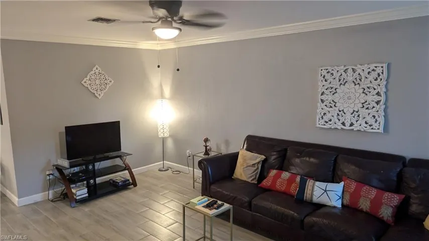 Living room featuring crown molding, ceiling fan, and light wood-type flooring