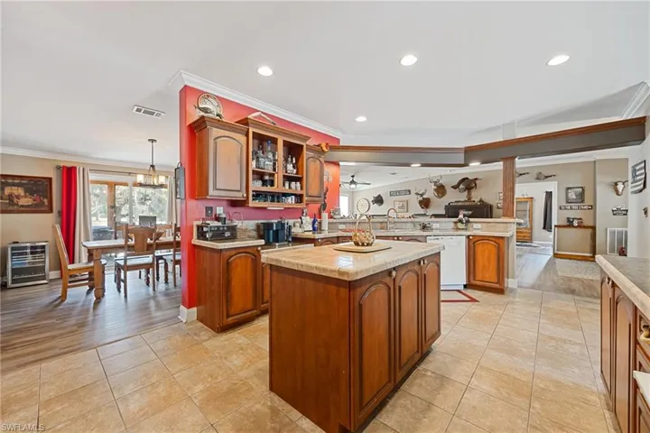 Kitchen with a peninsula, light countertops, open floor plan, dishwasher, and crown molding