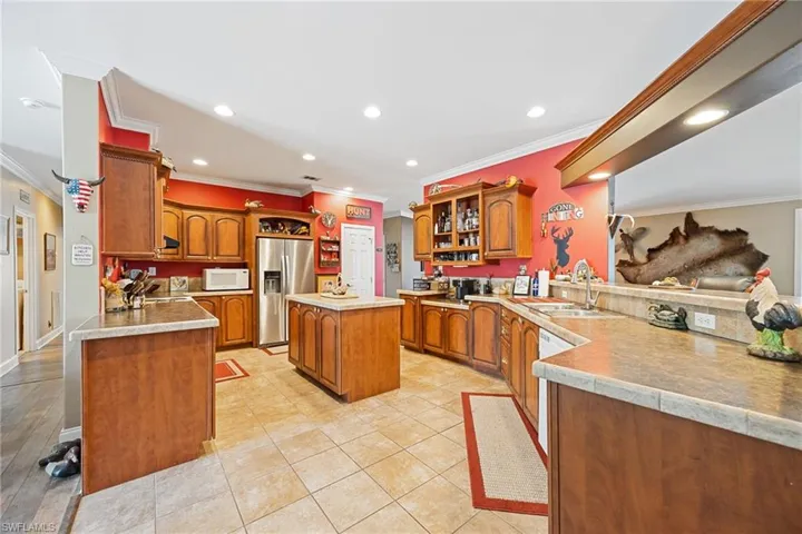 Kitchen featuring a peninsula, wood finish cabinetry, crown molding, white appliances, and recessed lighting