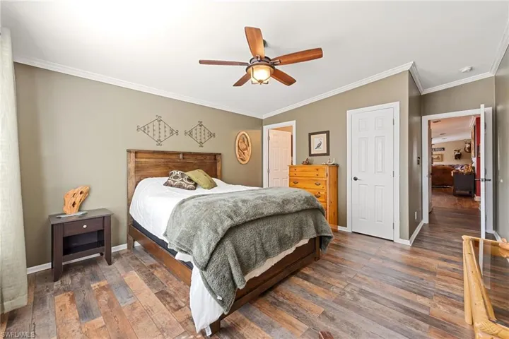 Bedroom featuring crown molding, dark wood-style floors, and ceiling fan