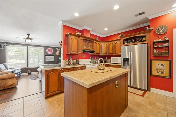 Kitchen with white appliances, open floor plan, ornamental molding, tile counters, and open shelves