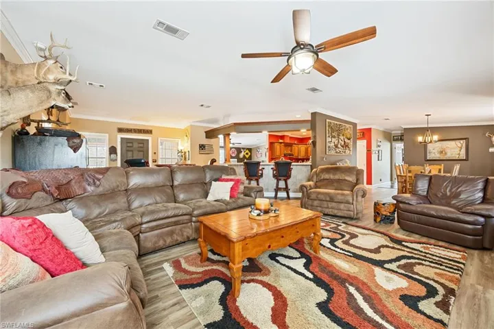 Living area featuring ornamental molding, ceiling fan, a chandelier, and wood finished floors