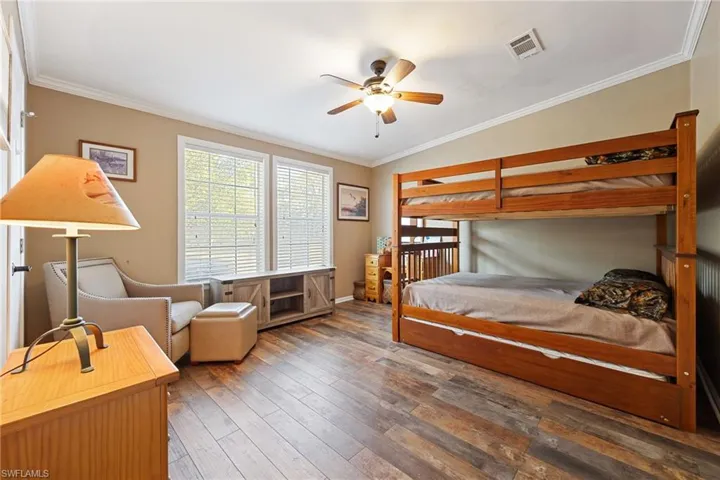 Bedroom with crown molding, wood-type flooring, ceiling fan, and lofted ceiling