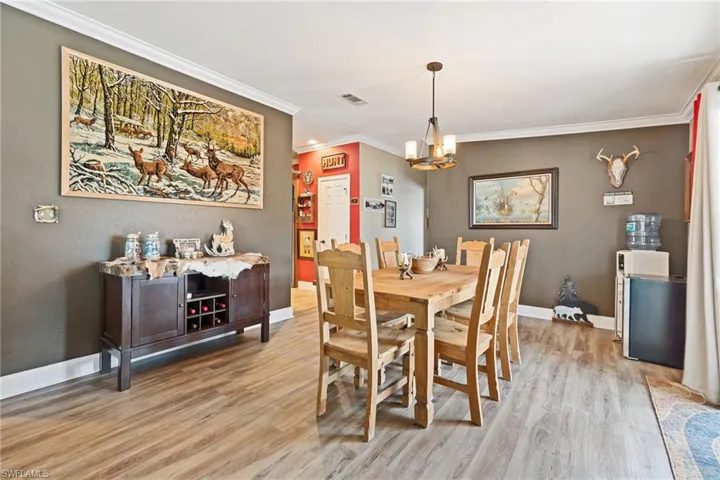 Dining space with ornamental molding, light wood-style floors, and suspended lighting