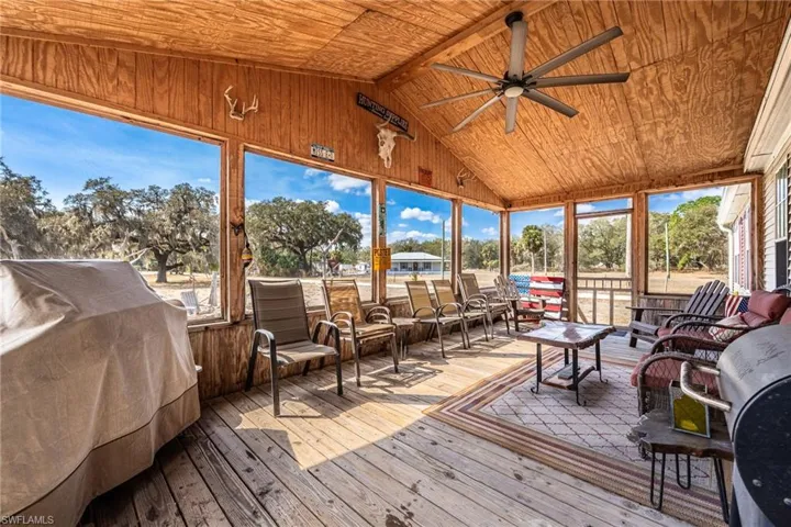 Sunroom / solarium featuring outdoor lounge area, ceiling fan, hardwood / wood-style floors, and a wooden ceiling with exposed beams