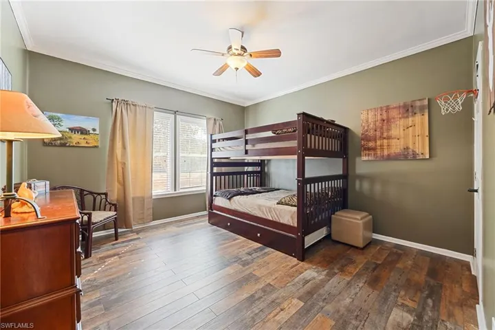 Bedroom featuring ornamental molding, dark wood-style floors, and ceiling fan