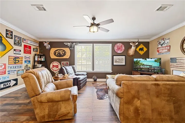 Living area featuring a ceiling fan, crown molding, and hardwood / wood-style floors