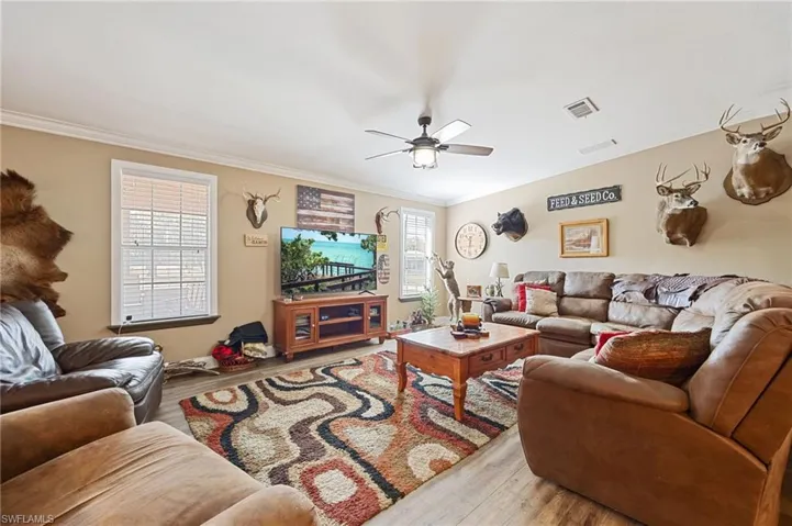 Living area with light wood-style floors, a ceiling fan, and ornamental molding
