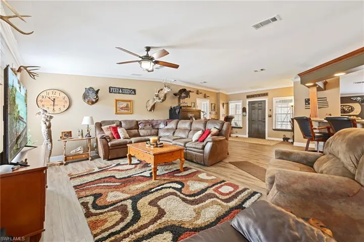 Living area featuring light wood-type flooring, ornamental molding, and a ceiling fan