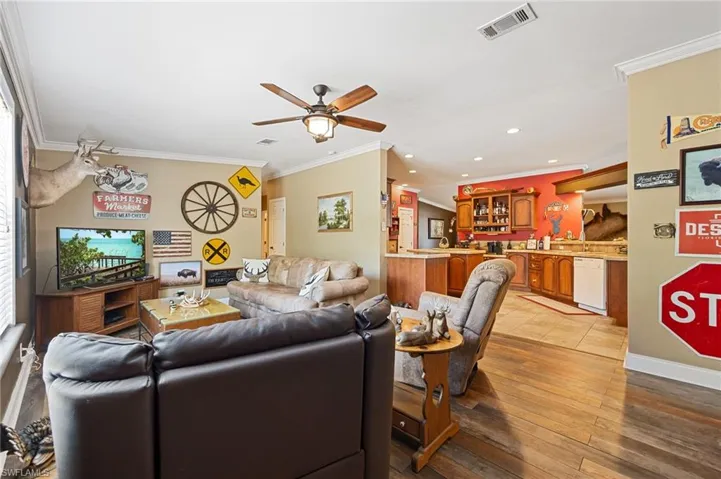 Living room featuring a ceiling fan, crown molding, light wood finished floors, and recessed lighting