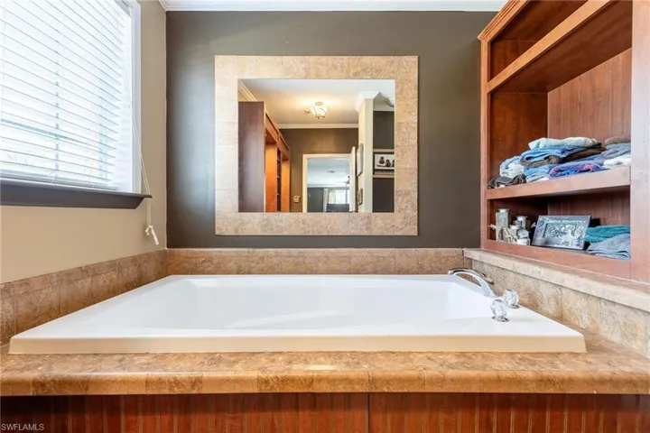 Full bathroom with ornamental molding and a bath
