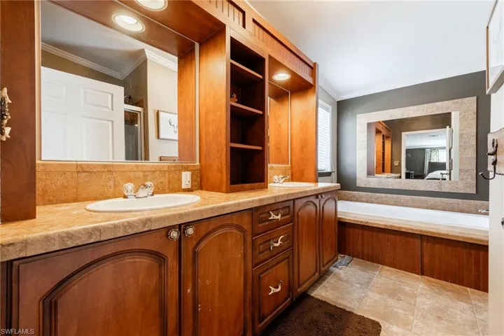 Full bath with double vanity, crown molding, and healthy amount of natural light