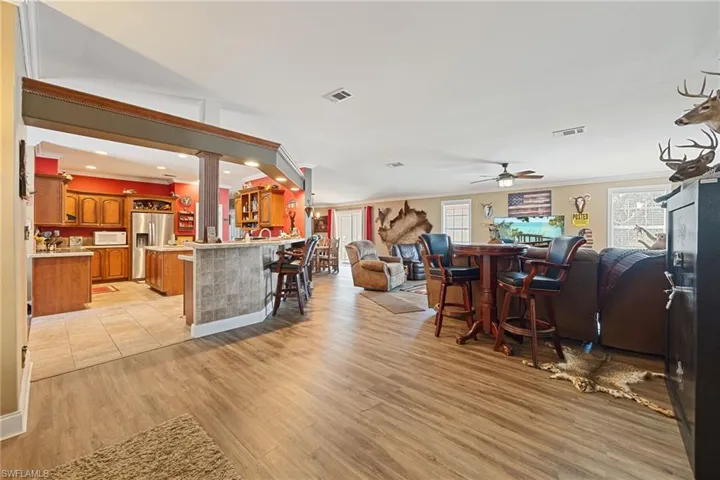 Living area featuring light wood-style flooring, decorative columns, ornamental molding, a ceiling fan, and recessed lighting