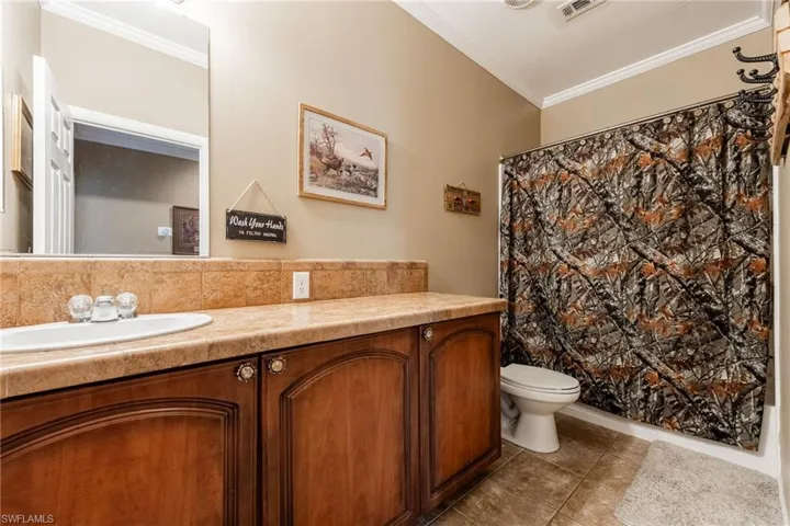 Bathroom with crown molding, vanity, and light tile patterned floors