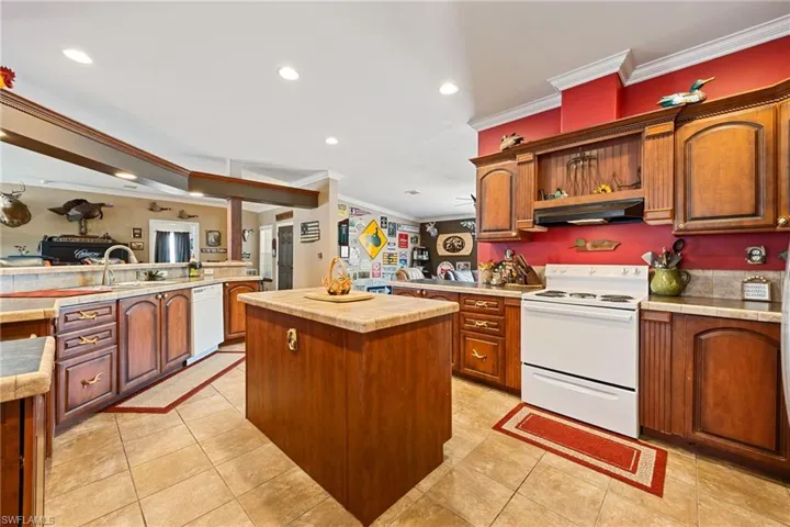 Kitchen with white appliances, light countertops, recessed lighting, ornamental molding, and light tile patterned floors