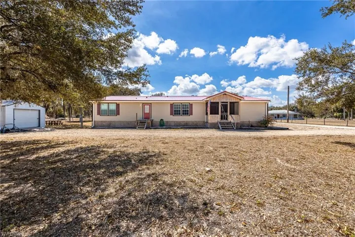Manufactured / mobile home featuring entry steps, a metal roof, a garage, and an outbuilding