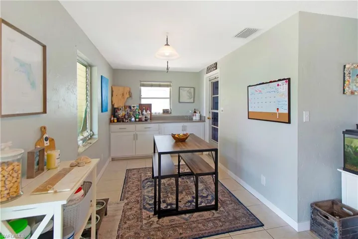 Kitchen with white cabinetry, hanging light fixtures, and light tile patterned floors