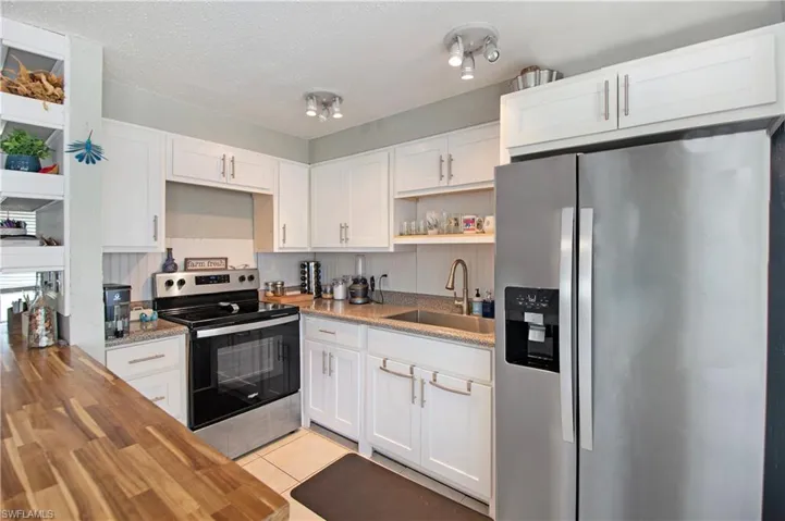 Kitchen featuring light tile patterned flooring, appliances with stainless steel finishes, sink, and white cabinets