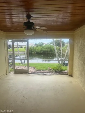 Unfurnished sunroom featuring ceiling fan and a water view