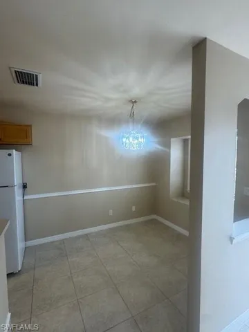 Unfurnished dining area featuring light tile patterned flooring and a chandelier