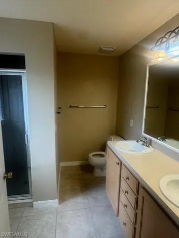 Full bath featuring double vanity, a stall shower, and light tile patterned floors