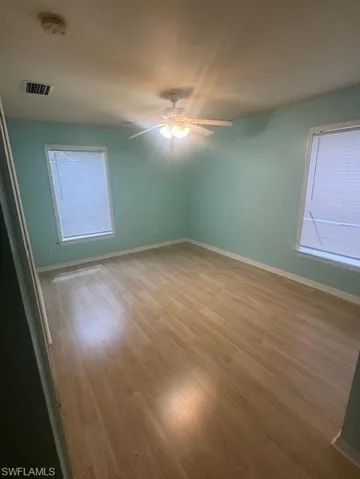 Empty room with wood finished floors, plenty of natural light, and a smoke detector