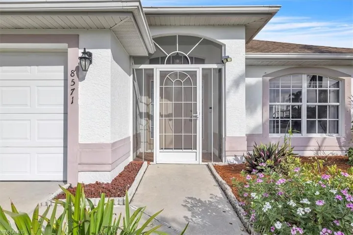 Property entrance with stucco siding, roof with shingles, and a garage
