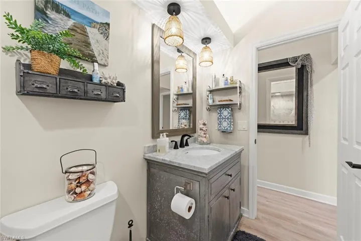 Bathroom featuring a single vanity with a marble-finish countertop, undermount sink, and dark-finish faucet