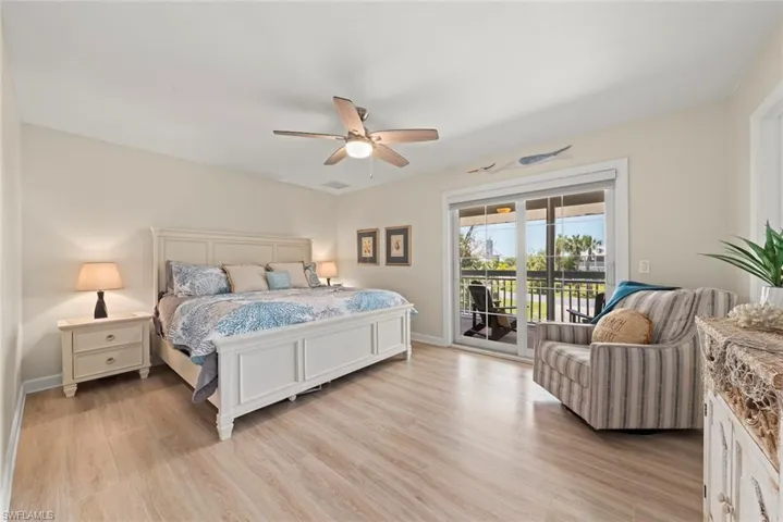 Spacious bedroom featuring wood-finish flooring, a ceiling fan with integrated lighting, and direct access to an outdoor balcony through sliding glass doors