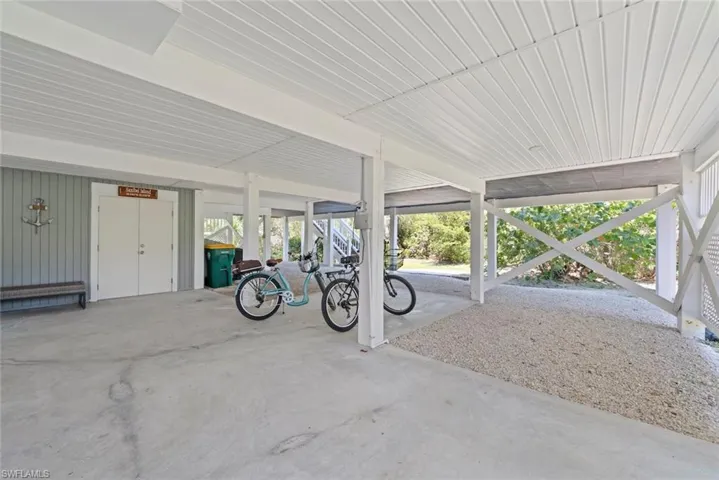 Covered parking area featuring a concrete slab and gravel, beadboard ceiling, and vertical siding