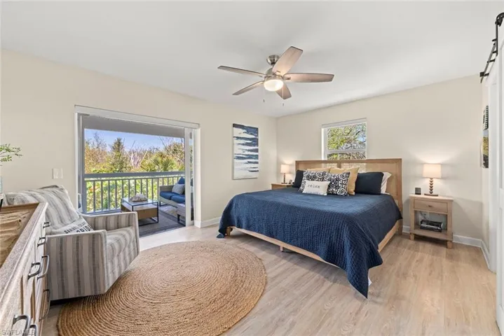 Bedroom featuring wood-finish flooring, a ceiling fan with light, and a sliding glass door opening to a private balcony