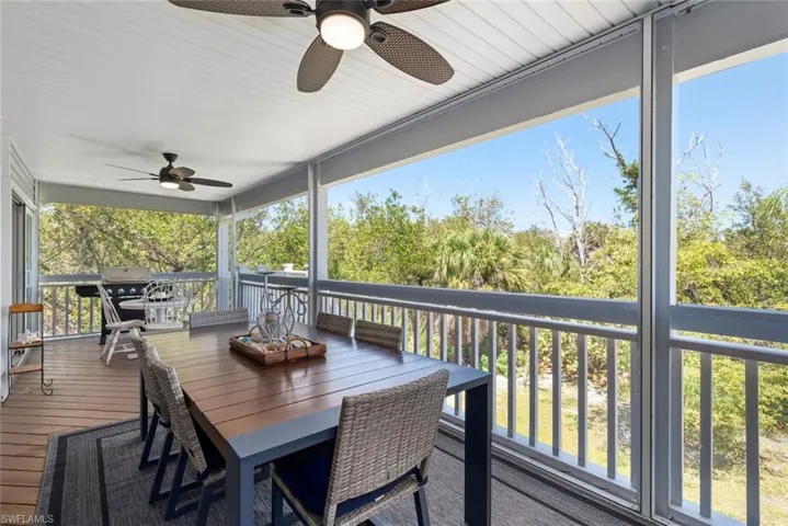 Expansive screened-in porch with wood-finish flooring, white paneled ceiling, and two ceiling fans