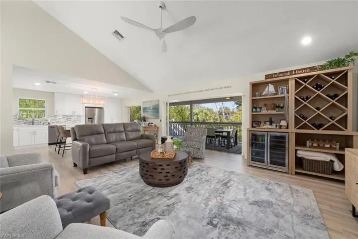 Vaulted ceiling living area featuring wood-finish flooring, a contemporary ceiling fan, and recessed lighting