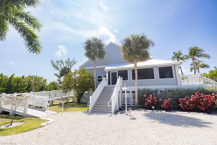 Light blue exterior with white trim, featuring a screened-in porch and an accessible ramp entry