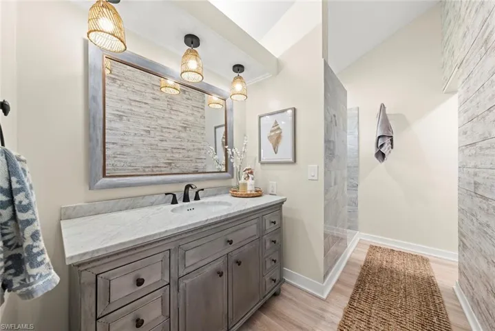 Bathroom featuring a weathered gray double vanity with a stone countertop, an undermount sink, and black hardware
