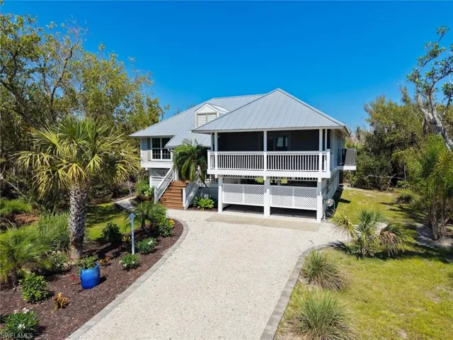 Raised coastal-style residence featuring a light gray metal roof and white exterior siding