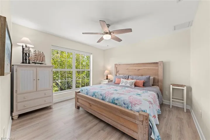 Bright room featuring wood-finish flooring, a large window, and a ceiling fan