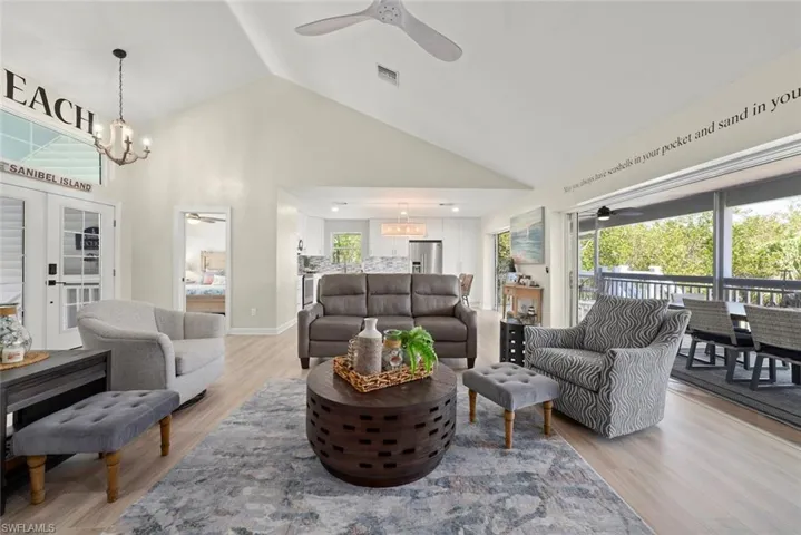 Vaulted ceiling living area featuring light wood-finish flooring, a contemporary ceiling fan, and direct access to a screened outdoor space
