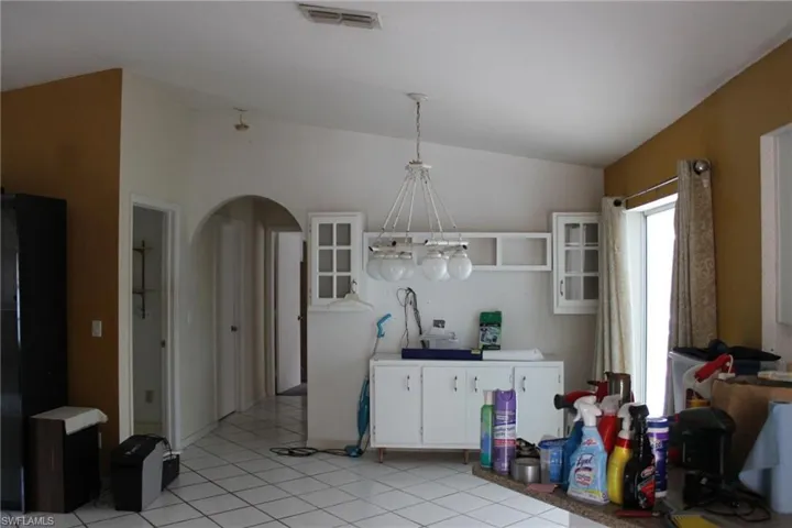 Breakfast area featuring white cabinetry, hanging light fixtures, lofted ceiling, and light tile patterned flooring