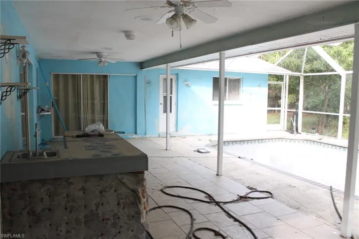 View of patio featuring screened enclosure, ceiling fan, and sink