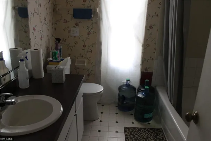 Full bathroom featuring shower / bathtub combination with curtain, tile patterned flooring, vanity, and toilet