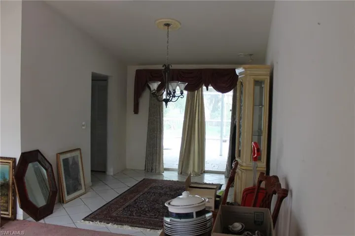 Dining room featuring light tile patterned flooring, lofted ceiling, and an inviting chandelier