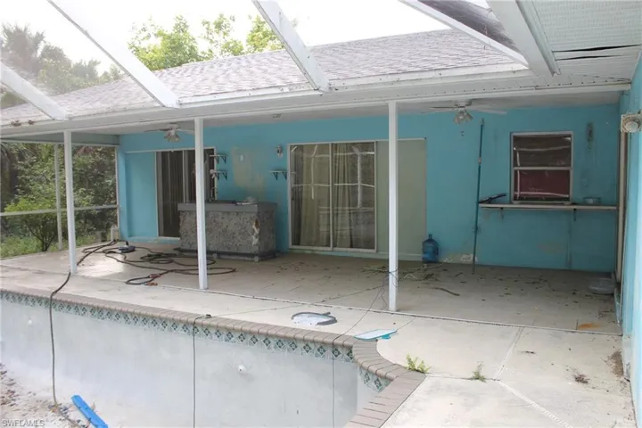 View of pool featuring screened enclosure, ceiling fan, and a patio area