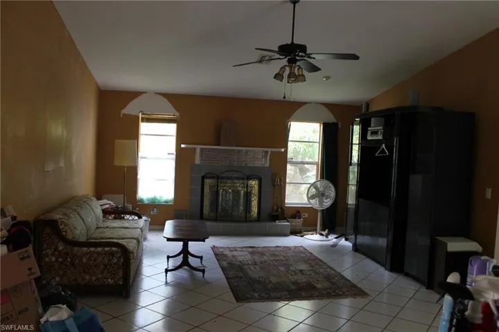 Tiled living room featuring a fireplace and ceiling fan