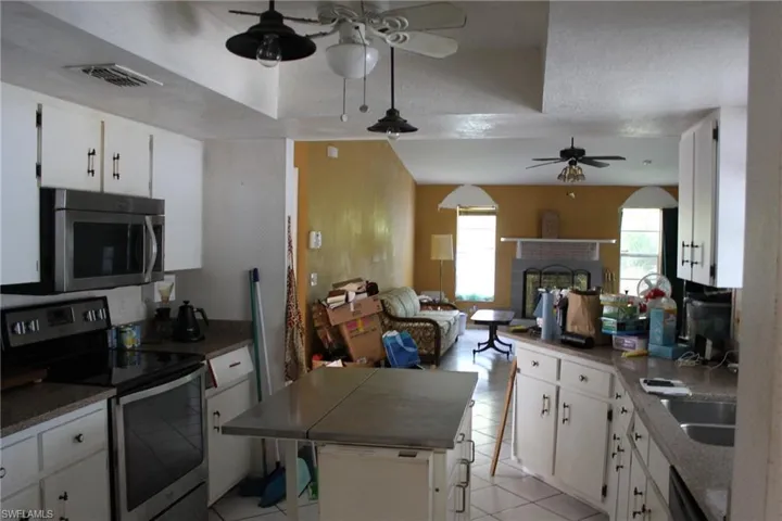 Kitchen with white cabinets, light tile patterned floors, a textured ceiling, and appliances with stainless steel finishes