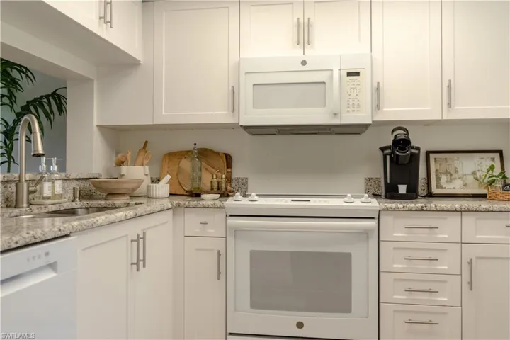 Kitchen featuring a sink, white cabinetry, and white appliances